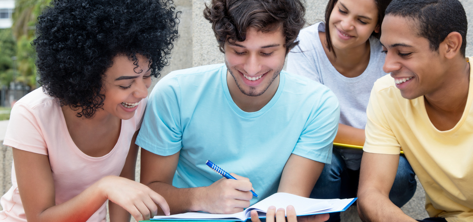 Eine Gruppe multiethnischer Studierender lernt im Sommer auf dem Campus im Freien.